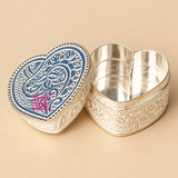 Open German Silver Heart-Shaped Kumkum Box with the matching engraved heart-shaped lid placed beside the container, showing the smooth reflective inner storage space, decorative floral engraved outer body, detailed lid design, compact low-profile shape and polished German silver finish, photographed on a premium beige studio background to demonstrate practical use for storing kumkum, roli, sindoor, turmeric or other small pooja essentials.