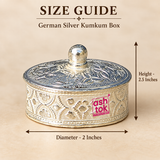 Size guide image of a German Silver Kumkum Box showing approximately 2 inch diameter and 2.5 inch overall height with clear measurement arrows, while preserving the traditional low-profile cylindrical shape, floral engraved body, broad matching lid, rounded knob and polished German silver finish, presented on a beige studio background to help customers understand the compact dimensions and proportions before purchasing for pooja use, gifting or decorative storage.