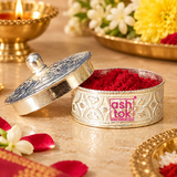 German Silver Kumkum Box shown open in a warm traditional pooja setting and filled with bright red kumkum powder, with the engraved lid placed beside the box and surrounded by tasteful flowers, festive decor and pooja accessories on a beige-toned surface, demonstrating practical use as a kumkum, roli or sindoor container for daily worship, religious ceremonies, festive rituals, wedding functions and traditional Indian occasions without any deity idol present.