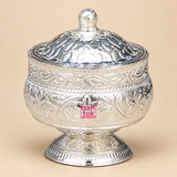 Traditional German Silver Kumkum Holder with a polished reflective silver finish, rounded floral engraved bowl-shaped body, matching domed lid with a small rounded top knob, decorative leaf and flower motifs, detailed border work and a short engraved pedestal base, photographed as a clean front-facing product image on a premium beige studio background, suitable for storing kumkum, roli, sindoor, turmeric and other small pooja essentials for daily worship, festive rituals, wedding ceremonies, home mandir use