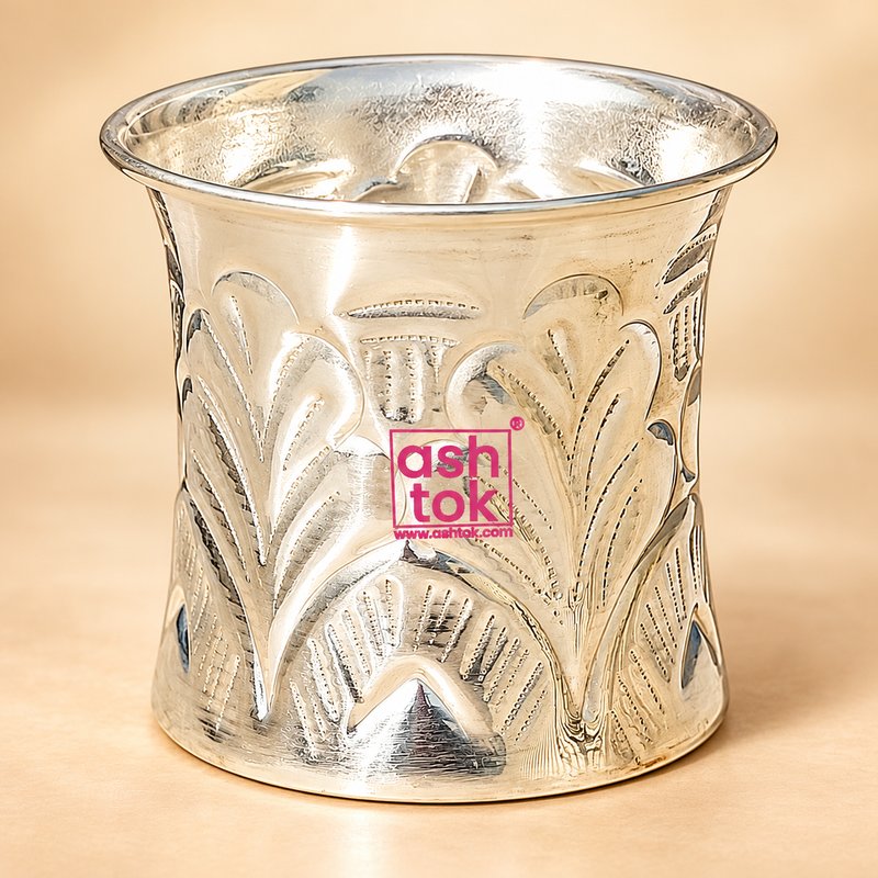 German Silver Nakshee Design Panchpatra displayed as a single traditional pooja vessel on a clean premium beige studio background, featuring a polished silver-tone finish, slightly flared top rim and detailed embossed floral and leaf-inspired Nakshee pattern across the exterior.