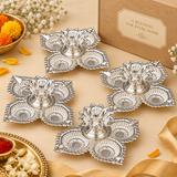 Multiple German Silver Pooja Diyas displayed together for bulk and gifting requirements, each featuring four decorative leaf shaped diya cups, detailed embossed borders and a raised floral central holder in a bright silver finish, suitable for wedding return gifts, Diwali gifts, corporate festive gifting, housewarming gifts, religious events, pooja functions and large quantity festive orders.