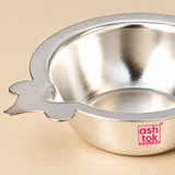 Detailed close-up image of a German Silver Puja Diya focusing on the polished neutral silver finish, broad smooth rim, reflective shallow bowl interior and distinctive flat side wick-holder extension, photographed on a premium beige studio background to clearly show the metal surface, rim thickness, bowl craftsmanship and functional wick-rest design for customers comparing details before purchase for daily puja and festive devotional use.