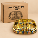 One complete gift bowls tray set presented with simple brown corrugated cardboard packaging on a clean beige studio background, featuring a rectangular golden serving tray with rounded corners and four matching round lidded bowls arranged inside, each bowl decorated with multicolor patterned outer bands and fitted with polished golden lids and small top knobs. The image shows one full set clearly outside the cardboard box to display the product design, hammered golden tray interior, coordinated decorative f