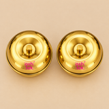 Two golden brass sindoor boxes with smooth rounded lids and compact bowl-shaped bases displayed from a different angle on a beige background, highlighting the shiny finish, symmetrical shape, and elegant traditional gift-item appearance.