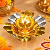 Gold and silver coated brass lotus diya illuminated with a bright flame during a traditional Indian pooja setting. The decorative oil lamp features alternating polished golden and silver lotus petals surrounding a glowing central brass bowl with a cotton wick. Marigold flowers, festive pooja decorations, and traditional brass accessories create a warm devotional atmosphere. Suitable for Diwali celebrations, daily pooja, home mandir decoration, religious ceremonies, and festive celebrations.