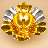 Top angled view of a decorative gold and silver coated brass lotus diya highlighting the symmetrical flower petal arrangement, reflective silver and golden finishes, deep circular oil bowl, and central wick holder. The lotus-inspired brass lamp has a polished metallic surface with a 5.5-inch diameter and 2-inch height. Suitable for traditional pooja ceremonies, Diwali decoration, home mandirs, religious festivals, wedding return gifts, and festive home decor.