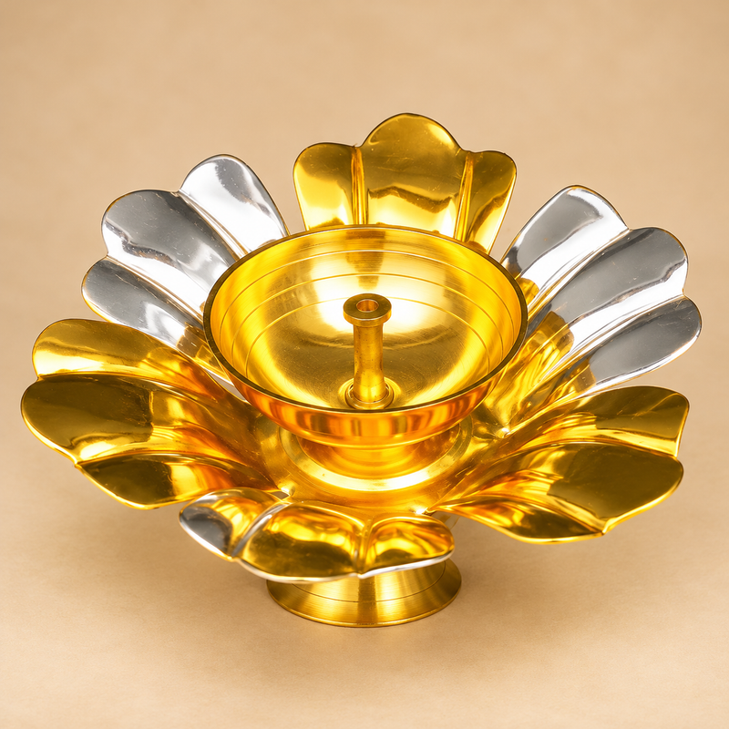 Single gold and silver coated brass lotus diya displayed against a premium beige studio background in a close three-quarter view. The decorative flower-shaped oil lamp features broad alternating golden and silver petals, a polished golden central bowl with a raised wick holder, and a circular pedestal base. This traditional brass diya has a 5.5-inch overall diameter and 2-inch height, making it suitable for home mandir decoration, Diwali pooja, festive arrangements, and traditional gifting.