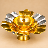 Single gold and silver coated brass lotus diya displayed against a premium beige studio background in a close three-quarter view. The decorative flower-shaped oil lamp features broad alternating golden and silver petals, a polished golden central bowl with a raised wick holder, and a circular pedestal base. This traditional brass diya has a 5.5-inch overall diameter and 2-inch height, making it suitable for home mandir decoration, Diwali pooja, festive arrangements, and traditional gifting.