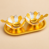 Elevated three-quarter view of a Gold and Silver Plated Dry Fruit Serving Set featuring two intricately engraved floral bowls with alternating gold and silver metallic petals, two matching ornamental gold spoons, and an oval golden serving tray with a textured beaded edge. The beautiful two-tone finish and traditional flower-shaped bowl design create an elegant decorative serving accessory for festive entertaining, special occasions, family gatherings, and gifting.