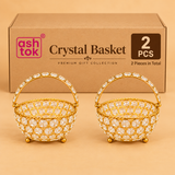 Set of 2 decorative crystal baskets featuring golden metal frames, sparkling clear round crystal embellishments, arched handles decorated with faceted stones, twisted golden rims and small spherical feet. Both baskets are displayed in front of a simple brown cardboard packaging box against a warm beige studio background. Each basket measures 7 inches in diameter and 8 inches in height, making the pair suitable for wedding return gifts, festive decorations, housewarming presents, decorative storage and speci
