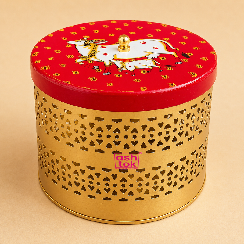 Decorative golden metal storage container with laser-cut design and red cow motif lid for dry fruit storage, return gifts, festive gifting, and home decor by Ashtok.