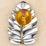 Top view of a traditional Leaf Design Brass Puja Diya featuring a decorative polished silver-coloured metallic leaf-shaped tray with a circular golden brass oil lamp bowl positioned towards the upper section of the leaf. The leaf tray displays a distinctive botanical-inspired design with multiple outward-curving lobes, rounded and pointed leaf segments, decorative vein-like contours, and a smooth mirror-finish silver surface. The circular brass diya bowl features a bright golden finish, concentric circular 