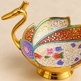 Detailed close-up view of a Meenakari duck design fruit bowl highlighting the craftsmanship of the golden duck neck, head and layered feather-shaped decorative panels. The close framing shows intricate floral and ornamental Meenakari patterns in white, red, blue, turquoise, purple, green and gold, along with the polished metal edging and raised circular pedestal base.