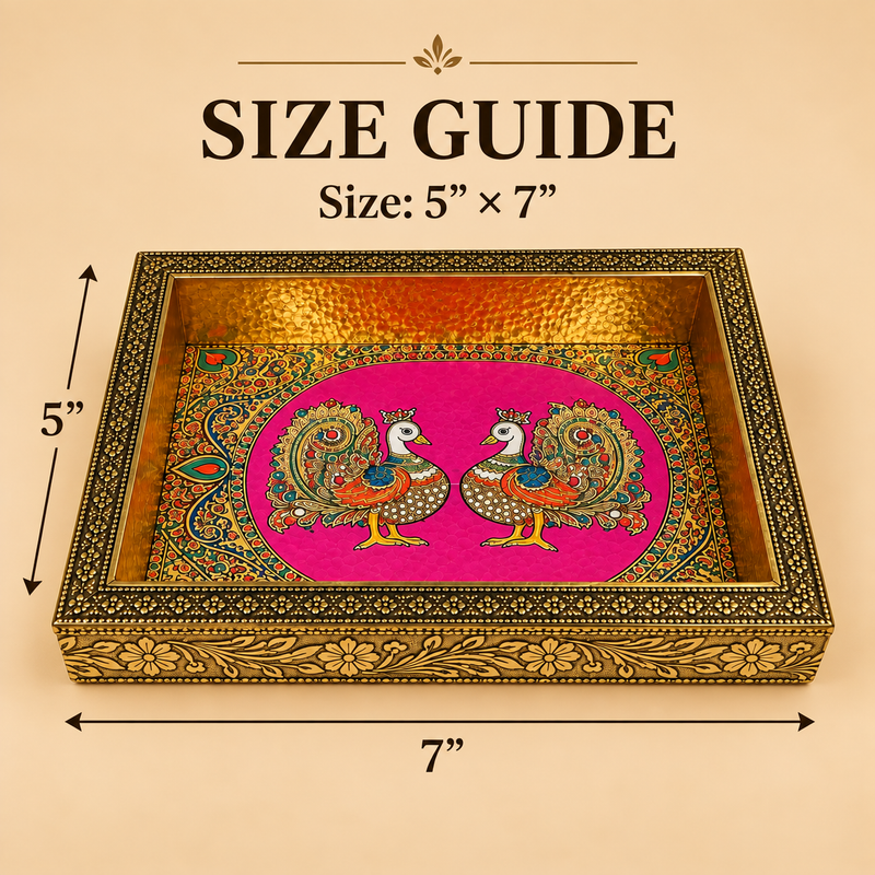 Comprehensive size guide diagram for a rectangular Meenakari peacock decorative wooden serving tray showing exact dimensions of 5 inches in width and 7 inches in length with measurement arrows on a warm beige background. The tray features a vibrant pink base with colorful dual peacock artwork, a hammered gold interior rim, and an engraved floral pattern along the outer brass frame.