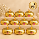 Set of 10 metal dryfruit gift boxes arranged in a premium beige bulk gifting display, featuring matching round golden containers with hammered finish, crystal-style top knobs and elegant return gift presentation for weddings, festive gifting and event orders.