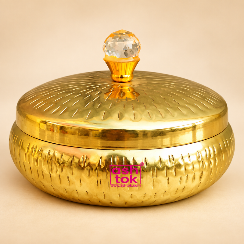 Metal dryfruit gift box with a polished golden finish, rounded hammered body, matching lid and elegant crystal-style knob, displayed on a premium beige studio background for a clean and professional Shopify product presentation.