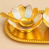 Detailed close-up photograph of a Gold and Silver Plated Dry Fruit Bowl showcasing intricately engraved flower-shaped petals, alternating polished golden and silver-toned sections, delicate floral and leaf patterns, and a matching engraved golden serving spoon. The photograph highlights the decorative petal design, polished metallic surfaces, raised bowl base, and ornamental detailing on the matching oval serving tray, making this an elegant dry fruit serving accessory for festive occasions and home