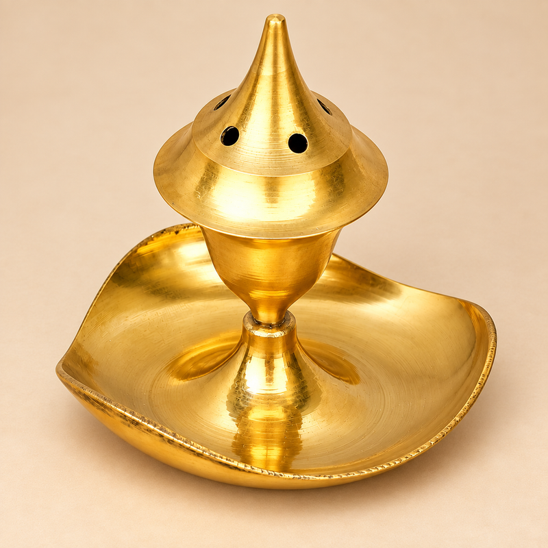 Golden brass agarbati flower incense holder shown from an alternate three-quarter angle on a premium beige background, highlighting the pointed conical top, circular ventilation holes, smooth polished body, raised pedestal support and curved leaf-shaped ash catcher, designed for holding incense during daily prayer, puja rituals, meditation and traditional home worship
