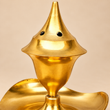 Detailed close-up image of a Golden Brass Agarbati Flower incense holder focusing on the tall pointed upper section, round ventilation holes, polished reflective brass chamber and the upper portion of the curved leaf-shaped ash catcher, photographed on a beige studio background to showcase the metal finish, craftsmanship and functional smoke ventilation design.