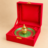 Decorative meenakari kumkum box placed on a round red and green meenakari plate on a beige background