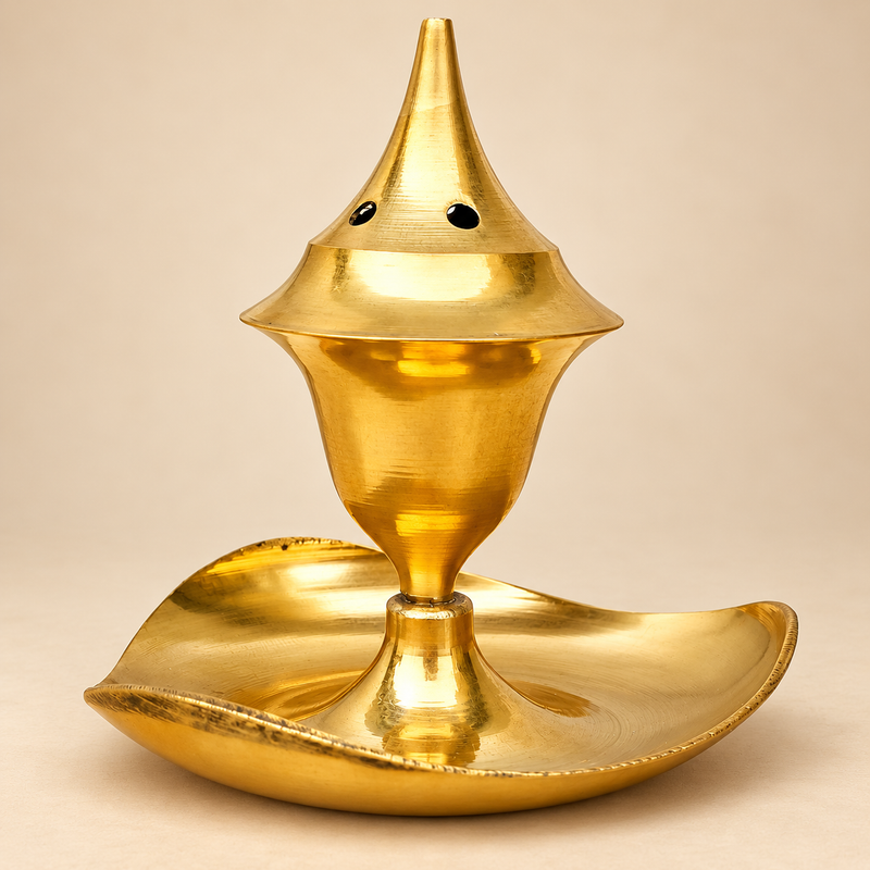 Polished golden brass agarbati flower incense holder displayed on a soft beige studio background, shown as a traditional metal incense burner with a tall pointed ventilated top and a curved leaf-shaped base that works as an ash catcher. The product has a warm golden brass finish with a smooth reflective surface, a tapered central body, and small round ventilation holes near the upper cone section. The lower tray has a gentle leaf-like curve with raised edges to collect ash neatly during use. The image prese