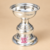 Polished silver finish Puja Deepam with a traditional pedestal design, wide shallow top bowl, rounded rolled rim, decorative narrow neck, bulbous central body with layered ring detailing and a broad stable circular base, photographed as a clean front-facing product image on a premium beige studio background for daily puja, festive worship, home temple use, pooja room setup, religious ceremonies, return gifting and traditional Indian devotional occasions.