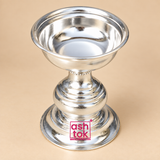 op angle view of a traditional silver finish Puja Deepam showing the wide circular bowl opening, polished reflective interior, smooth rounded rim, decorative pedestal stem, layered body contours and broad stable base, presented against a premium beige studio background for a clear view of the deepam bowl design suitable for oil, wick lighting, daily puja, festive rituals and home temple use.
