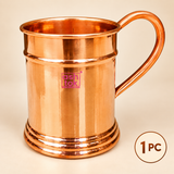 One piece pure copper mug with polished finish, sturdy curved handle, smooth cylindrical body and decorative base, presented on a premium beige background for individual use, gifting and cocktail serving.
