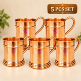 Set of 5 pure copper beer mugs arranged together on a premium beige background, each featuring a polished copper body, curved handle and decorative base, suitable for gifting, parties, hospitality use and beverage serving.