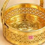 Detailed close-up view of Round Shaped Brass Puja Basket, Phool Butti and Flower Basket highlighting the intricate floral cutwork, heart-inspired decorative pattern, polished golden brass finish, sturdy handle joints, embossed Om symbol and traditional religious motifs inside the base. The close-up also shows the ASHTOK logo on the front, emphasizing the detailed craftsmanship and decorative finish of the basket.