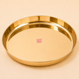 High-polished round brass puja plate with straight raised sides and an Ashtok logo sticker centered on a neutral backdrop.
