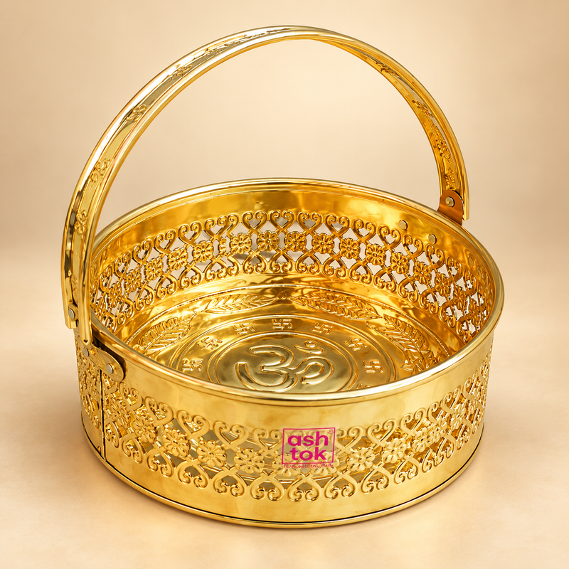Round shaped brass puja basket, phool butti and flower basket with a rich polished golden brass finish, decorative floral cutwork pattern, sturdy curved carrying handle and embossed religious detailing inside the base. The basket features the ASHTOK logo on the front and is professionally photographed on a premium beige studio background, suitable for puja flowers, temple offerings, festive rituals, home mandir use and traditional gifting.