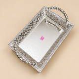 Elevated three-quarter view of a decorative silver rectangular serving tray on a clean beige background, showing the spacious reflective base, intricate open lattice side walls, ornate rim detailing, polished beaded handles at both ends and compact raised feet, designed to give customers a clear view of the tray interior, depth, proportions and decorative metalwork for home serving, special occasions, wedding gifting and festive presentation.