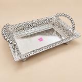 Rectangular silver serving tray shown from a top angled view on a premium beige studio background, featuring a reflective flat base, intricate openwork filigree side walls, decorative beaded border detailing, raised ball-style handles on both short sides and small supporting feet, presented in a clean ecommerce style to clearly show the tray shape, ornamental metalwork and polished silver finish for serving, gifting, festive presentation and decorative use.