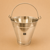 Stainless steel bathroom bucket with sturdy carrying handle on a beige studio background, ideal for home bathrooms, bathing, water storage, and everyday household use.