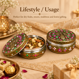 Lifestyle photograph titled 'Lifestyle / Usage - Perfect for dry fruits, sweets, mukhwas and festive gifting.' Set on a beige fabric backdrop with a burning tea light lantern, golden ribbon, and traditional Indian sweets, an open Meenakari box is shown filled with mixed dry fruits including cashews, almonds, and raisins. A second closed box beside it showcases the full peacock lid and floral side border detailing.
