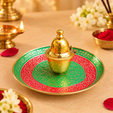 Meenakari kumkum box and matching plate styled as a traditional gifting set with a closed red gift box on a beige background