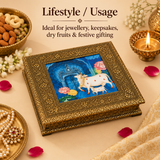 Lifestyle image of the Wood Cow Design Box displayed in an elegant festive setting to show its practical use as a decorative storage box for jewellery, keepsakes, small accessories, and gifting. The image highlights the rich traditional design, gold embossed frame, and colorful cow artwork while presenting the box as a premium home décor and gift item.