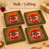Product arrangement titled 'Bulk / Gifting - Perfect for return gifts, festive gifting & special occasions.' Four identical rectangular wooden Meenakari trays with vibrant elephant centerpieces are arranged in a 2x2 grid layout on a beige background, accompanied by a wrapped golden gift box tied with a ribbon, jasmine flower petals, and a brass oil lamp.