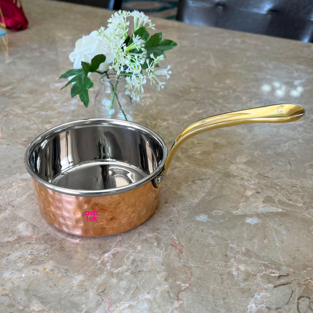 Artisan-crafted copper saucepan with brass grip handle, ideal for daily cooking and serving in style.